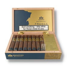 Open box of 16 Macanudo Emissary France Robusto cigars with branded presentation, information card and individually cellophaned cigars displayed inside.